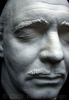 a white sculpture of a man's face with his eyes closed