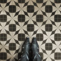 a pair of black shoes sitting on top of a tiled floor