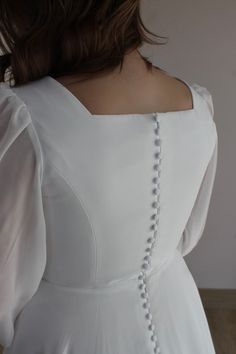 the back of a woman's white dress with pearls