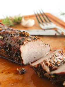 a piece of meat sitting on top of a cutting board next to a knife and fork