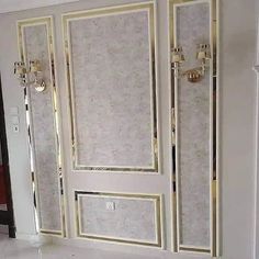 an empty room with white walls and gold trim on the doors, in front of a mirror