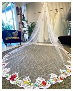 a bed with a white net hanging from it's headboard and flowers on the bedspread