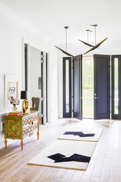 an elegant entry way with blue doors and white rugs on the hardwood flooring