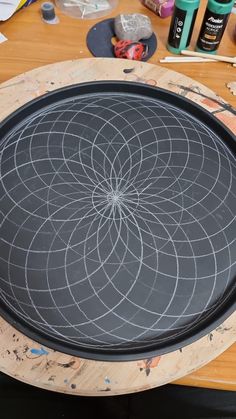 a wooden table topped with a black tray covered in white circles and paintbrushes