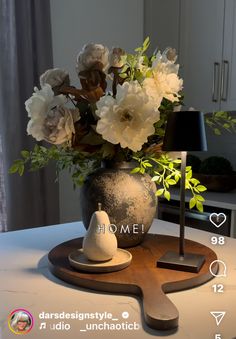 a vase filled with flowers sitting on top of a wooden table next to a lamp