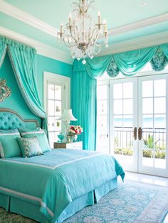 a bedroom decorated in blue and green with a chandelier