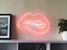 a neon sign that is on top of a shelf next to a potted plant