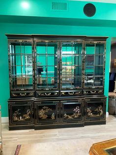 an ornate black china cabinet with glass doors in a living room or dining room area