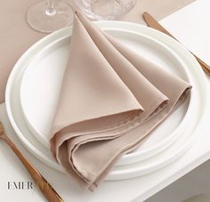 the napkins are folded on top of each other near silverware and wine glasses