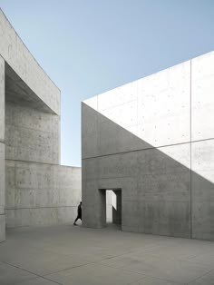 a person standing in an open space between two concrete buildings