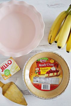 bananas, yogurt and other ingredients on a white wooden table with a pink bowl