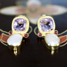 This courtly presentation of an exquisitely hand faceted amethyst and baroque pearl has an almost medieval look. The stones are set in a 14k gold settings filigree design and accented with two tiny garnets. Post backs for pierced ears. Size: 3/4 inch. Elegant Purple Gemstone Pearl Earrings, Elegant Purple Pearl Earrings For Formal Occasions, Elegant Amethyst Earrings As A Gift, Garnet Drop Earrings, Pink Garnet, Pearl Earrings Wedding, Spring Jewelry, Gold Pearl Earrings, Garnet Earrings