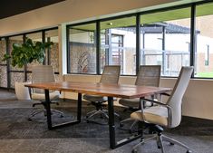 an empty conference room with chairs and a wooden table in front of large glass windows