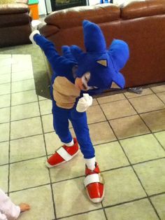 a child dressed as sonic the hedge standing in front of a couch