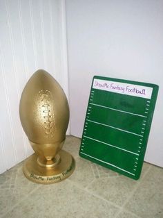 a golden egg sitting next to a green football game board on the floor in front of a white door