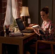 a woman sitting at a desk reading a book