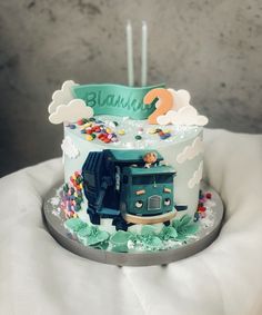 a birthday cake decorated with a truck and clouds