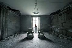 a woman is standing in an abandoned room