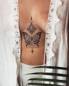 a woman's chest with a butterfly tattoo on her left side ribcage