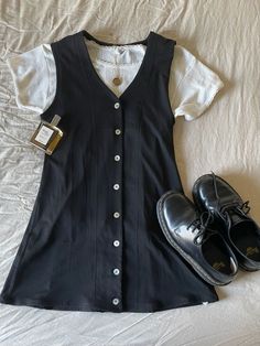 a pair of black shoes sitting on top of a bed next to a white shirt