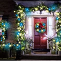 christmas wreaths and lights on the front door of a house