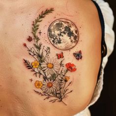 a woman's back with flowers, butterflies and a full moon tattoo on it