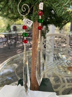 two glass pendulums hanging from a tree branch with numbers and beads attached to them