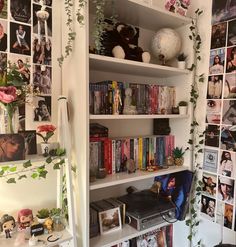 a bookshelf filled with lots of books next to a wall covered in pictures