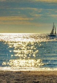 a sailboat in the distance on an ocean beach