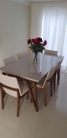 a dining room table with chairs and a vase filled with flowers