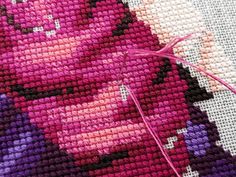 a close up of a cross - stitch pattern with pink and purple designs on it