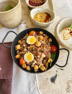 a bowl filled with food sitting on top of a table next to other bowls and utensils