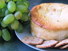 a plate with bread, grapes and crackers on it next to a bunch of green grapes