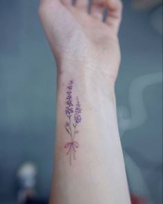 a small purple flower tattoo on the wrist