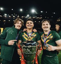 three men standing next to each other while holding onto the same trophy in their hands