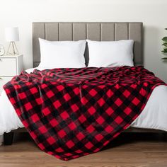 a red and black checkered blanket on top of a bed in a room with white pillows