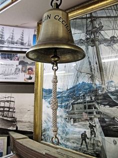 a bell hanging from the side of a wall next to pictures and framed photos on a wall