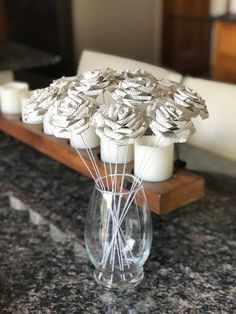 a vase filled with white candles sitting on top of a counter