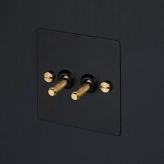 two black and gold knobs on the side of a black wall mounted light switch