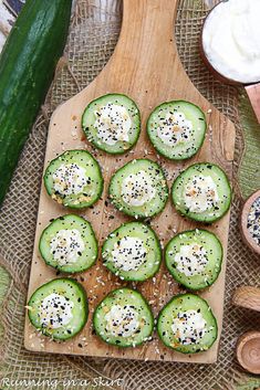 cucumbers are arranged on a cutting board with cream cheese and black pepper sprinkles