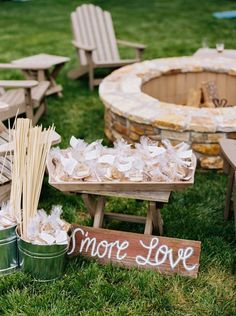 there are some wooden chairs and tables in the grass near a fire pit with marshmallows