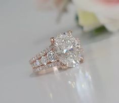 a close up of a diamond ring with flowers in the background