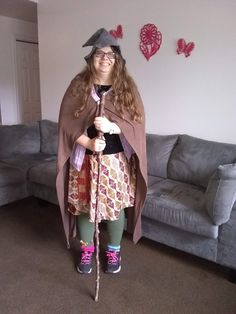 a woman dressed up as a witch holding a stick in her hand while standing next to a couch