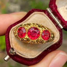 An early Victorian era three stone band with beautiful heavily chased details throughout the front and sides of the ring. The three fiery paste stones truly glow in the light - they're a bright red hue with deep orange undertones. The band is meticulously engraved with an ornate floral motif. A rich bloomed finish completes this very special heirloom piece. Metal: 14K Yellow Gold (acid tested) Weight: 6.6 grams Center Paste: Approx 6.5 mm diameter Side Paste Stones: Approx 5.4 mm diameter each R Antique Three Stone Gold Jewelry, Antique Gold Three-stone Jewelry, Antique Three-stone Ruby Wedding Ring, Vintage Gold Ruby Ring With Three Stones, Vintage Three-stone Ruby Ring Gift, Vintage Three Stone Ruby Ring Gift, Vintage Three Stone Ruby Ring For Wedding, Antique Three Stone Ruby Ring, Antique Three-stone Ruby Ring Gift