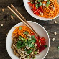 two bowls filled with noodles and vegetables on top of a wooden table next to chopsticks