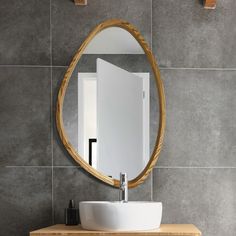 a bathroom sink sitting under a mirror on top of a wooden counter next to a wall mounted faucet