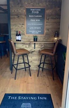 a bar with two stools in front of it and a sign that says the staying inn