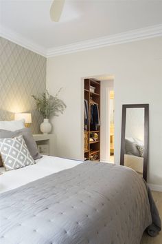 a bedroom with a bed, dresser and mirror in it's corner next to a closet