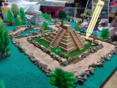 a cake that is shaped like a pyramid with trees and rocks around it on a table