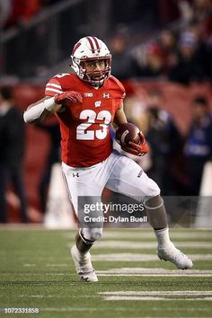 a football player running with the ball in his hands during a game against american football team